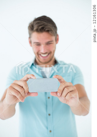 Happy young man looking at his mobile phone 12161306