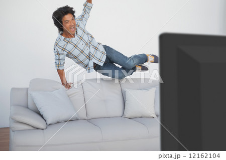 Happy soccer fan cheering while watching tv Happy soccer fan cheering while watching tv 12162104