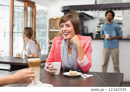 Pretty brunette enjoying her latte with a friend 12162595