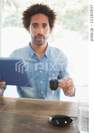 Casual man having coffee while using tablet 12162647