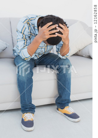 Tensed football fan sitting on couch 12162858