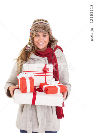 Happy blonde in winter clothes holding gifts 12163118