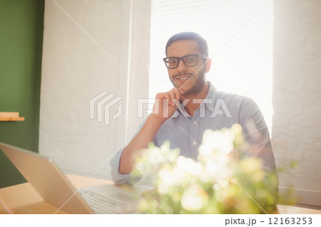 Casual businessman using his laptop at his desk 12163253