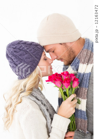 Attractive couple in warm clothing holding flowers 12163472