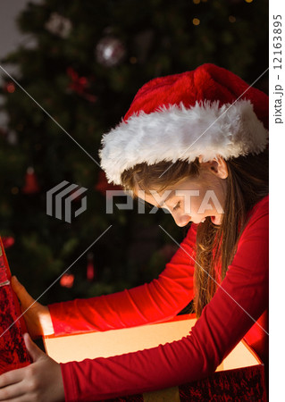 Little girl opening a magical christmas gift Little girl opening a magical christmas gift 12163895