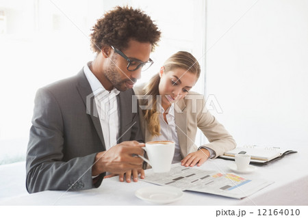 Business people having coffee looking at newspaper Business people having coffee looking at newspaper 12164010