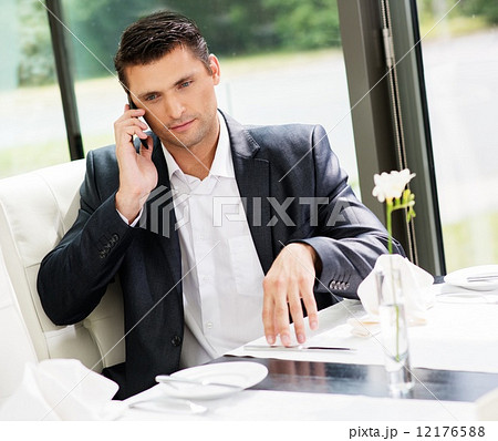 Handsome businessman talking over mobile phone in restaurant Handsome businessman talking over mobile phone in restaurant 12176588