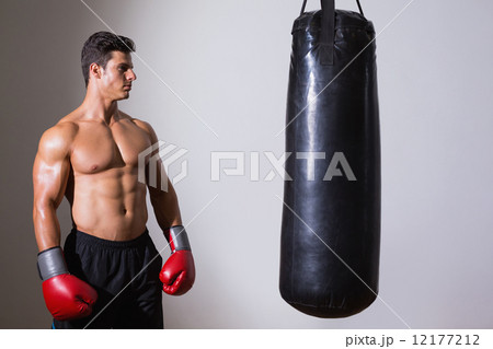 Shirtless muscular boxer looking at punching bag Shirtless muscular boxer looking at punching bag 12177212