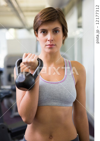 Fit brunette lifting kettlebell looking at camera Fit brunette lifting kettlebell looking at camera 12177312