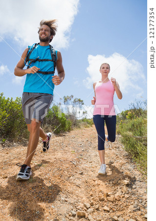 Fit attractive couple jogging down mountain trail 12177354