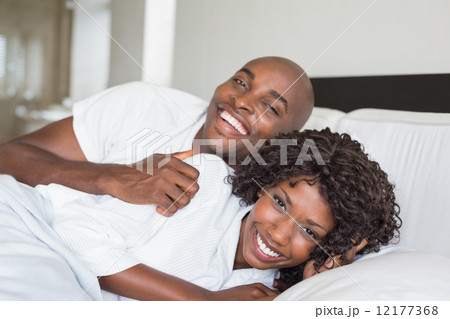 Happy couple lying in bed together Happy couple lying in bed together 12177368