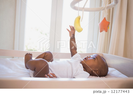Adorable baby boy lying in his crib playing with mobile Adorable baby boy lying in his crib playing with mobile 12177443