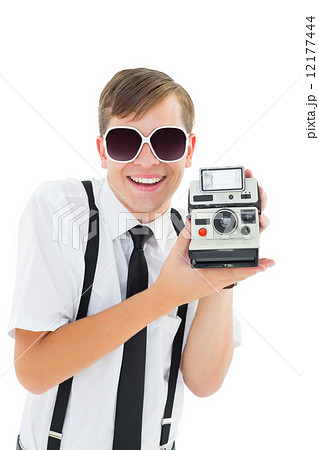 Geeky hipster holding a retro camera Geeky hipster holding a retro camera 12177444