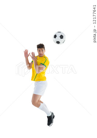 Football player in yellow jersey jumping to ball Football player in yellow jersey jumping to ball 12177641