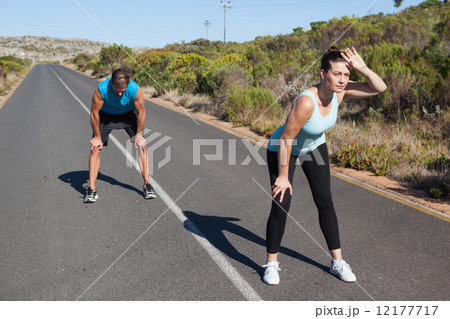 Athletic couple taking a break from jogging on the open road Athletic couple taking a break from jogging on the open road 12177717