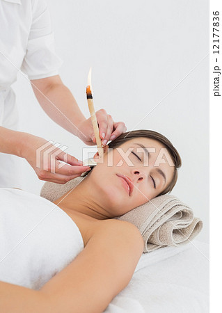 Beautiful woman receiving ear candle treatment at spa center Beautiful woman receiving ear candle treatment at spa center 12177836