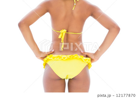 Fit girl in yellow bikini mid section rear view 12177870