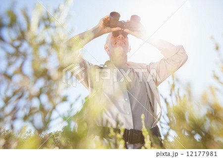 Hiker standing on country trail looking through binoculars 12177981