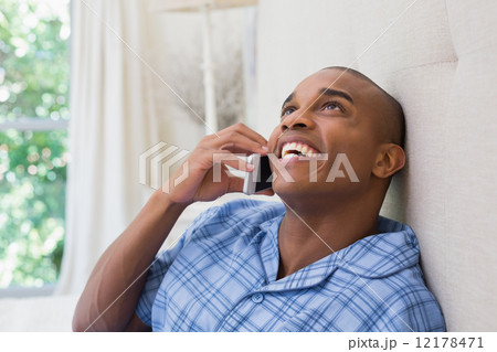 Happy man sitting on bed and talking on phone Happy man sitting on bed and talking on phone 12178471