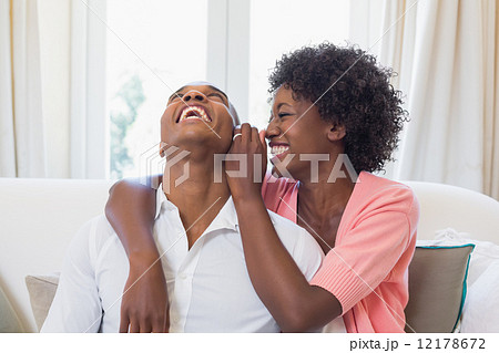 Pretty woman telling a secret to partner on couch 12178672