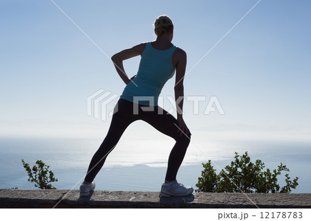 Fit woman stretching her legs looking out to sea 12178783