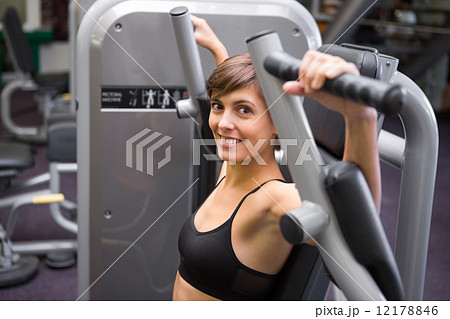 Happy brunette using weights machine for arms Happy brunette using weights machine for arms 12178846