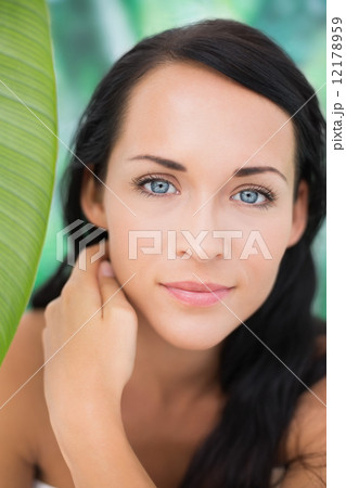 Beautiful nude brunette smiling at camera with green leaf 12178959