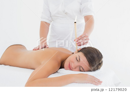 Beautiful woman receiving ear candle treatment at spa center Beautiful woman receiving ear candle treatment at spa center 12179020
