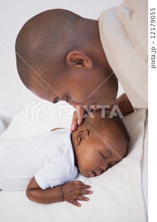Baby boy sleeping peacefully on couch with father kissing head 12179055