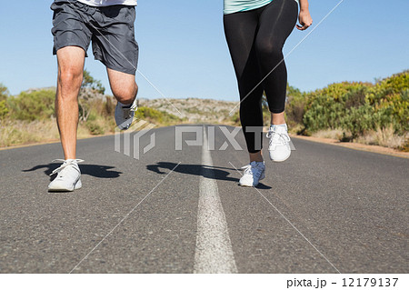 Fit couple running on the open road together 12179137