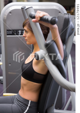 Athletic brunette using weights machine for arms Athletic brunette using weights machine for arms 12179491