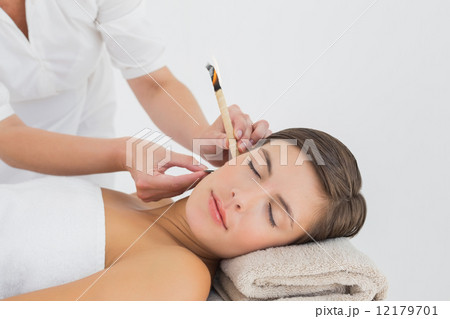 Beautiful woman receiving ear candle treatment at spa center Beautiful woman receiving ear candle treatment at spa center 12179701