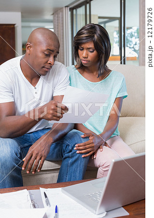 Worried couple calculating bills on the couch Worried couple calculating bills on the couch 12179726