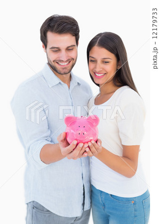 Happy couple holding their piggy bank Happy couple holding their piggy bank 12179733