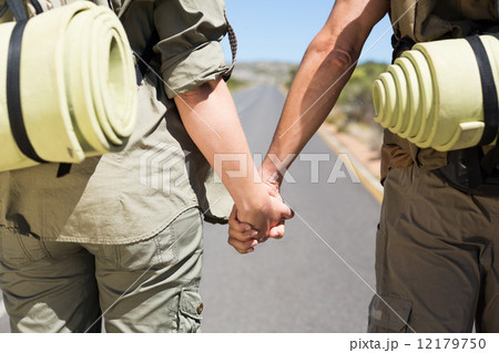 Hitch hiking couple standing holding hands on the road Hitch hiking couple standing holding hands on the road 12179750