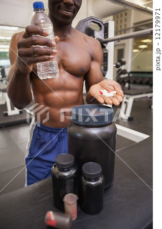 Shirtless muscular man holding vitamin pills 12179971