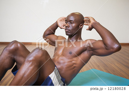 Muscular man doing abdominal crunches in gym Muscular man doing abdominal crunches in gym 12180028