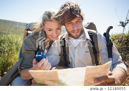Hiking couple taking a break on mountain terrain using map and c 12180055