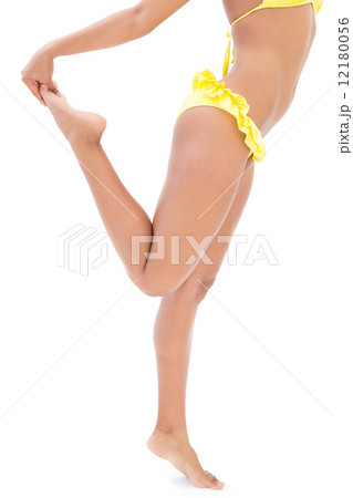 Athletic girl in yellow bikini stretching her leg 12180056
