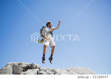 Handsome hiker jumping at the summit smiling at camera 12180057