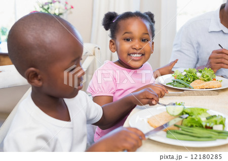 Family enjoying a healthy meal together with daughter smiling at Family enjoying a healthy meal together with daughter smiling at 12180285
