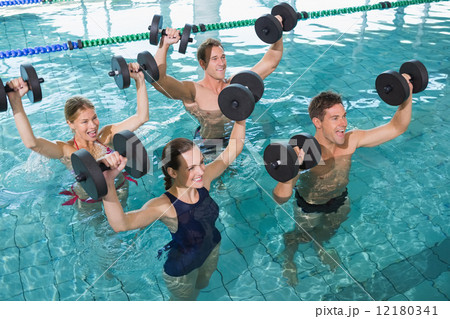 Happy fitness class doing aqua aerobics with foam dumbbells 12180341