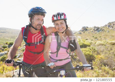 Fit cyclist couple smiling together on mountain trail 12180555