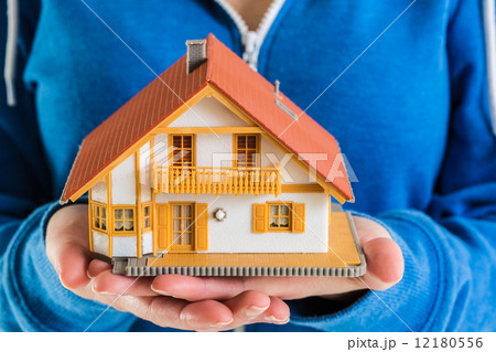 Hands holding miniature house model 12180556