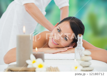 Beautiful brunette enjoying a back massage smiling at camera 12180712