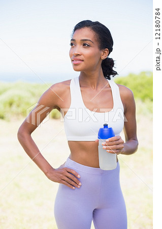 Fit woman holding sports bottle smiling 12180784