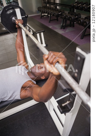 Determined muscular man lifting barbell in gym 12180907