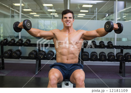 Muscular man exercising with dumbbells in gym Muscular man exercising with dumbbells in gym 12181109