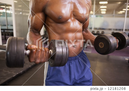 Muscular man exercising with dumbbells in gym Muscular man exercising with dumbbells in gym 12181208