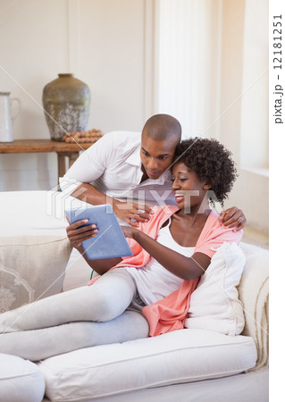 Happy couple relaxing together on the couch using tablet 12181251